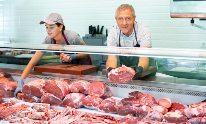 Positive,Male,Elderly,Salesman,In,Apron,And,Disposable,Gloves,Shows Incremento en oferta de productos cárnicos busca reducir precios e mejorar ingesta. Foto La Hora: Shutterstock