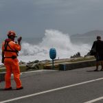 Guardia costero de Taiwán advierte a un residente que contempla las grandes olas provocadas por el tifón Bavi.