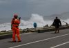 Guardia costero de Taiwán advierte a un residente que contempla las grandes olas provocadas por el tifón Bavi.