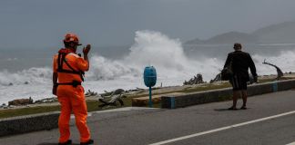 Taiwán, Japón y China se preparan ante avance del tifón Bavi Guardia costero de Taiwán advierte a un residente que contempla las grandes olas provocadas por el tifón Bavi.
