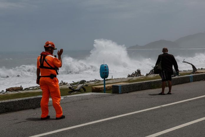 tifon bavy taiwan japon Guardia costero de Taiwán advierte a un residente que contempla las grandes olas provocadas por el tifón Bavi.