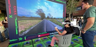 Una chica sentada y con gafas de realidad virtual frente a una pantalla que muestra su visión en un proyecto captado por los estudiantes.