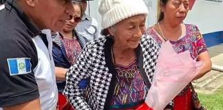 Juana Santiago Chel abandona el hospital con un ramo de flores en las manos tras recibir el alta médica. Según medios locales de Quiché, continuará su recuperación en la vivienda de una de sus hijas mientras su defensa prepara acciones legales por el desalojo.