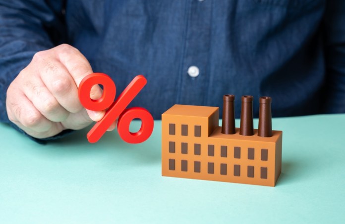 A,Man,Holds,A,Percent,Sign,Near,A,Factory.,The Empresas recurren a la bolsa para financiarse y llegar a más inversionistas. Foto La Hora: Shutterstock