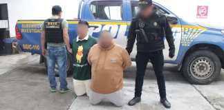 Los dos detenidos permanecen arrodillados junto a agentes de la PNC tras el operativo en Santa Elena Barillas, Villa Canales.