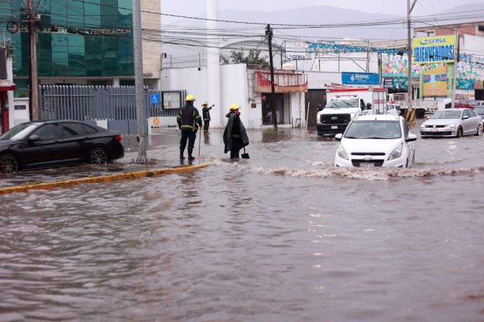 Bomberos atienden una emergencia en calle inundada debido a las fuertes lluvias en Pachuca por tormenta tropical. Foto La Hora: EFE